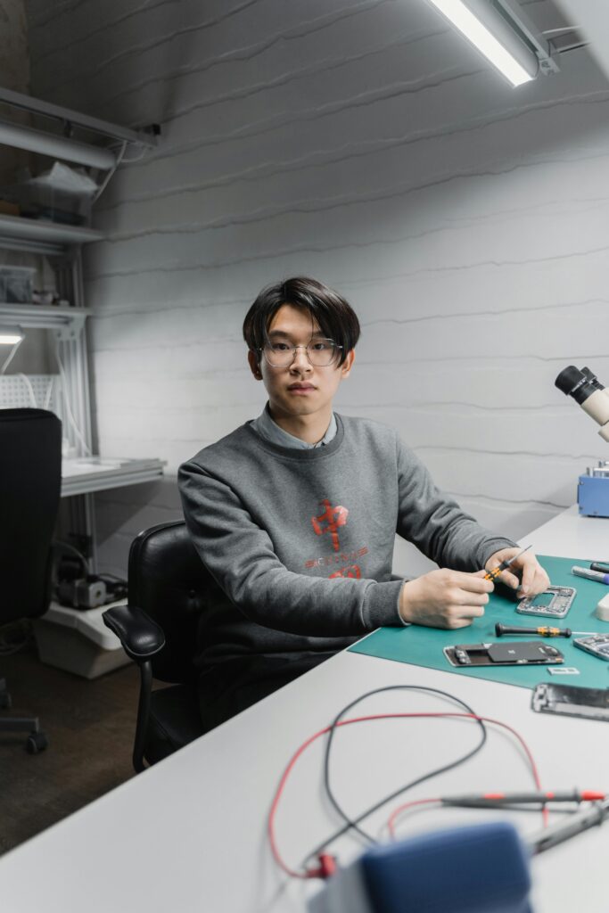Focused young man working on electronic devices in a modern workspace.